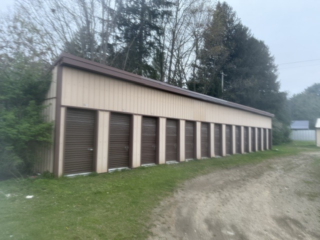 Storage building with a line of roll-up unit doors along a gravel drive